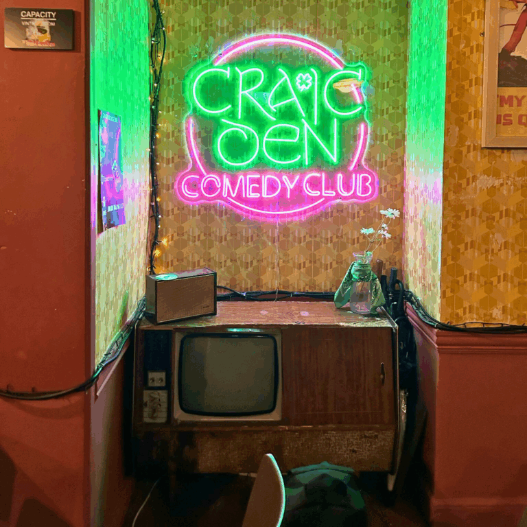 Craic Den Comedy Club logo neon sign above vintage TV set